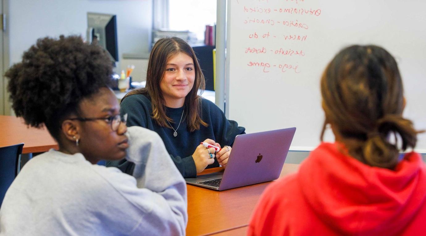 Student with laptop listens to discussion.